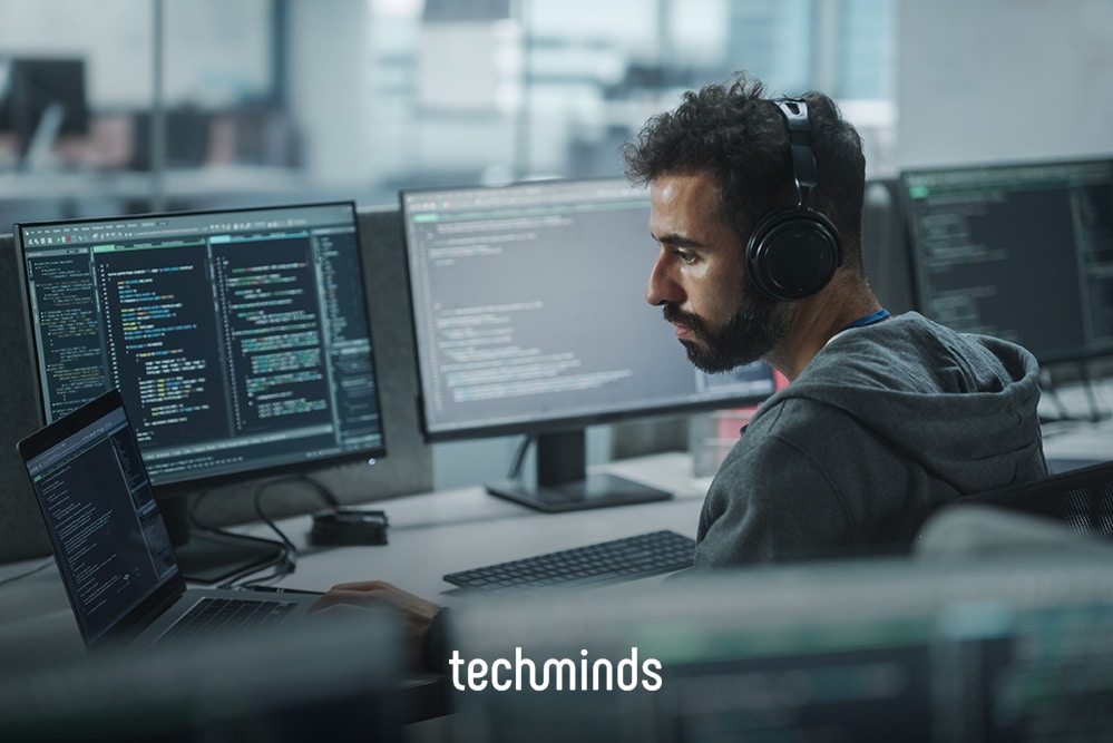 Entwickler mit Kopfhörern an Monitoren mit Code, Jobprofil Application Engineer