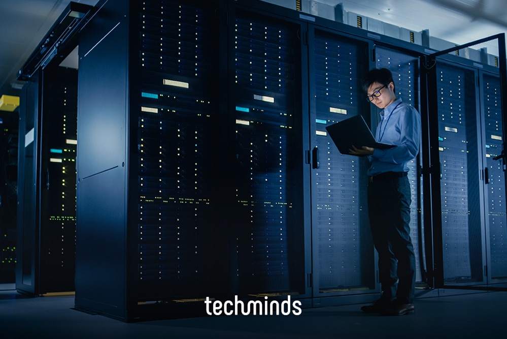 Netzwerkadministrator mit Laptop zwischen Serverschränken, Jobprofil Netzwerkadministrator