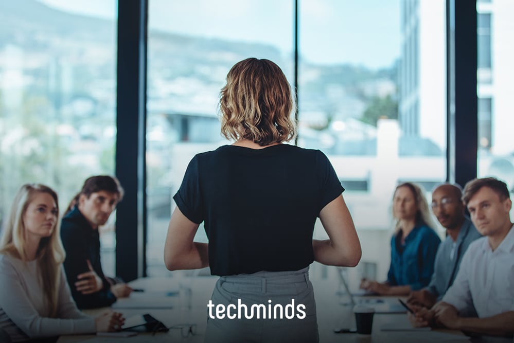 Scrum Master steht vor dem Team am Besprechungstisch, Jobprofil Scrum Master