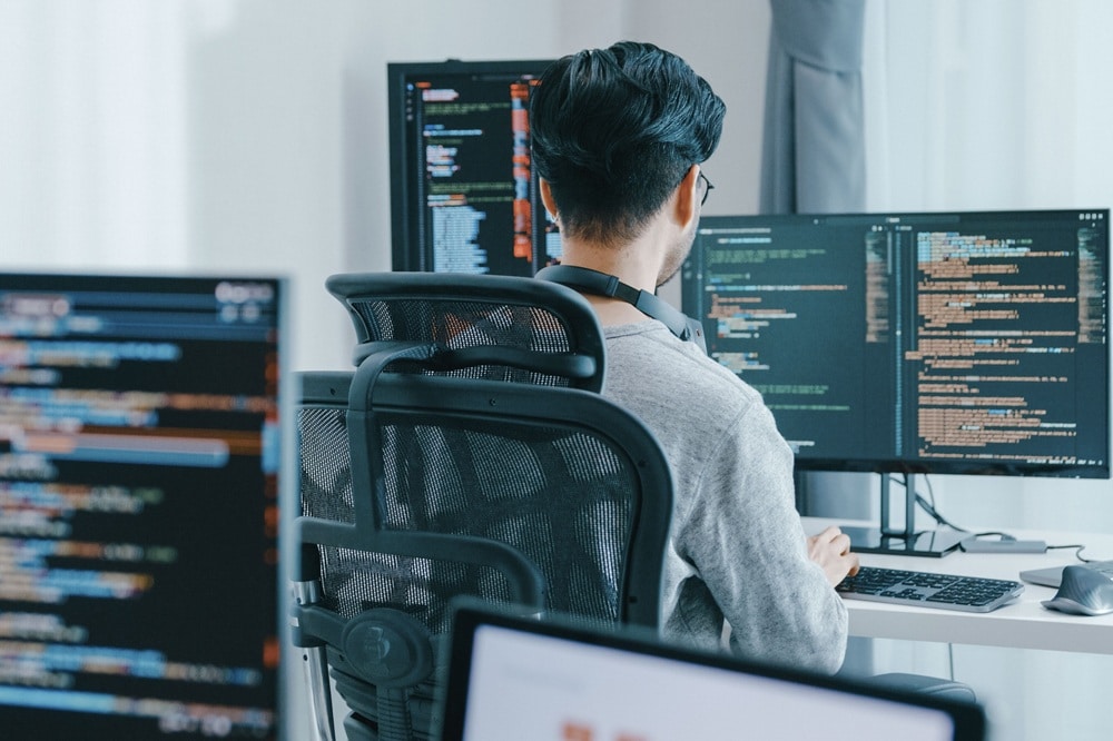 Data Scientist arbeitet am PC, Code auf PC