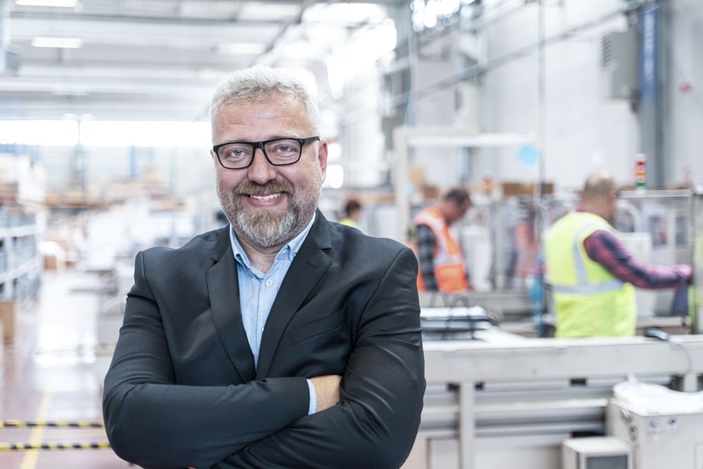 Geschäftsführer mit verschränkten Armen in der Produktionshalle, Personalberatung Mittelstand