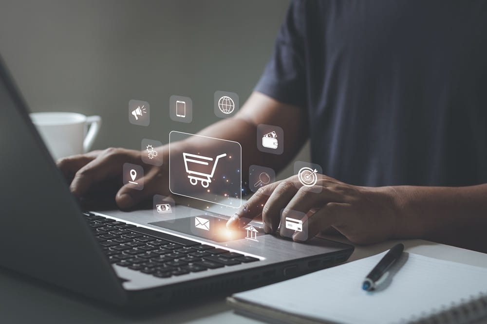 Hände am Laptop mit eingeblendeten Onlineshopping-Symbolen