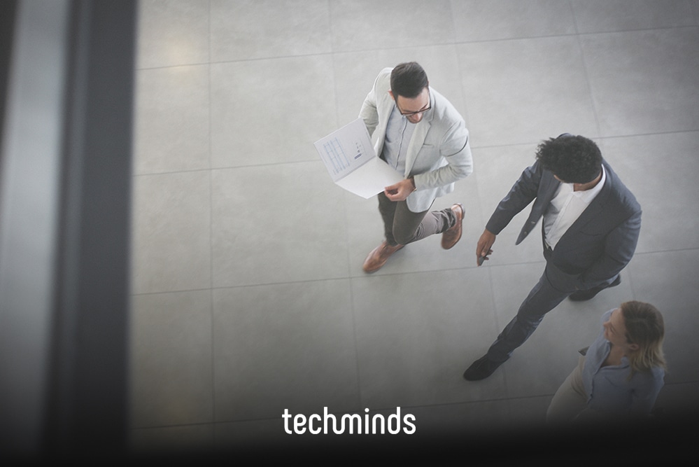Zwei Personen im Gespräch von oben, auf dem Boden das TechMinds-Logo