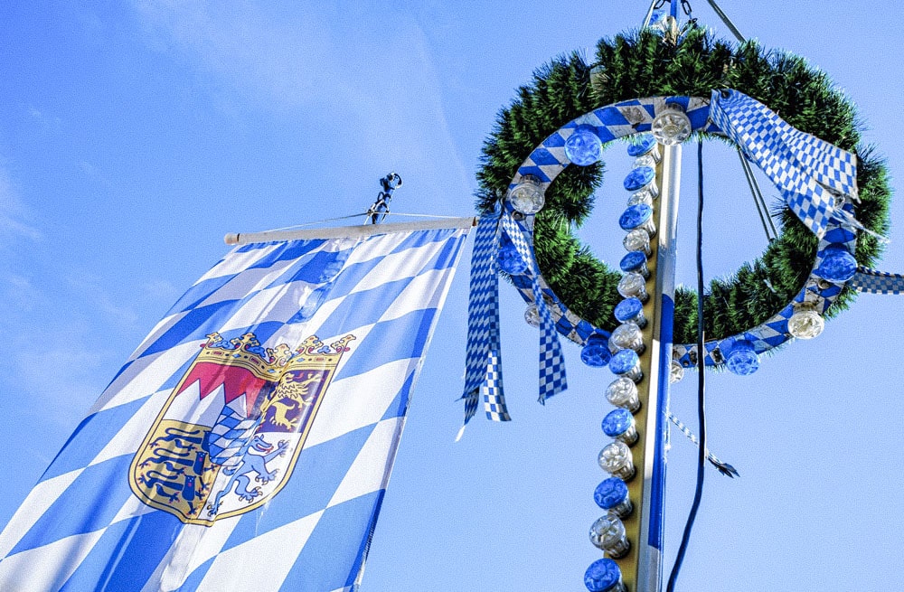 Weiß-blauer Maibaum vor blauem Himmel in Bayern