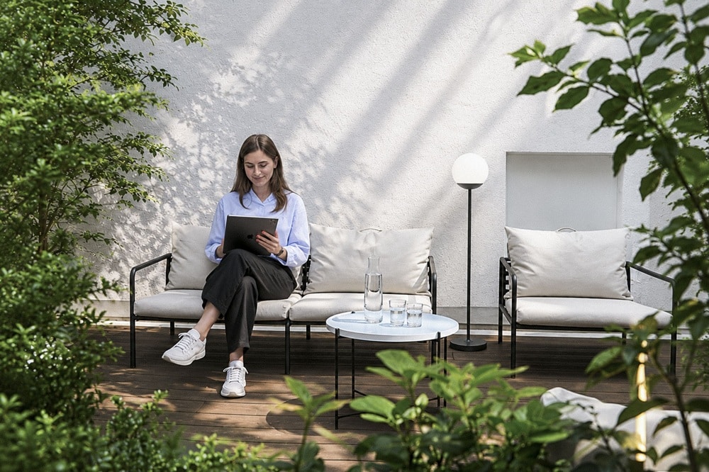 TechMinds-Teammitglied arbeitet entspannt mit einem Tablet auf der modernen Büro-Terrasse.