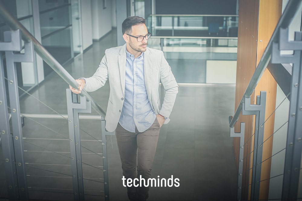 Professional man in smart-casual attire pausing on a modern office building staircase.
