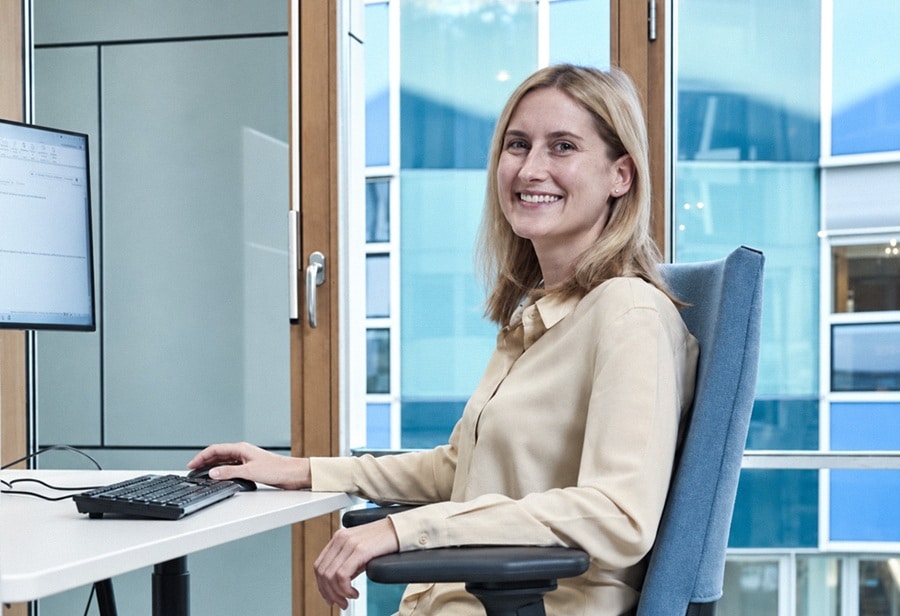 Denise Wiegner von TechMinds lächelt am Schreibtisch im Team Office – warum TechMinds überzeugt.