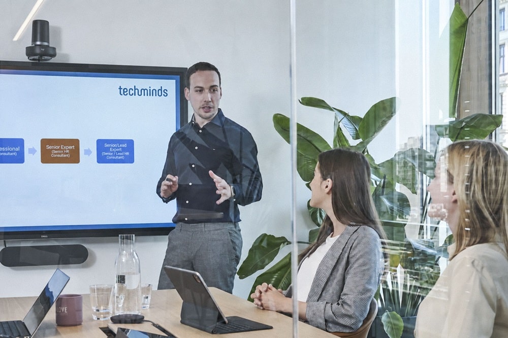 Florenz Klasen erläutert zwei Kolleginnen im TechMinds Meetingraum die Executive-Search-Strategie