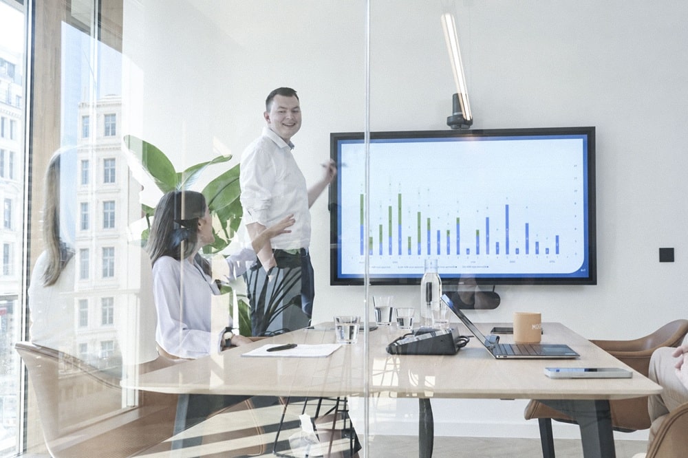 TechMinds Team im Konferenzraum, Präsentation eines Diagramms mit Kennzahlen